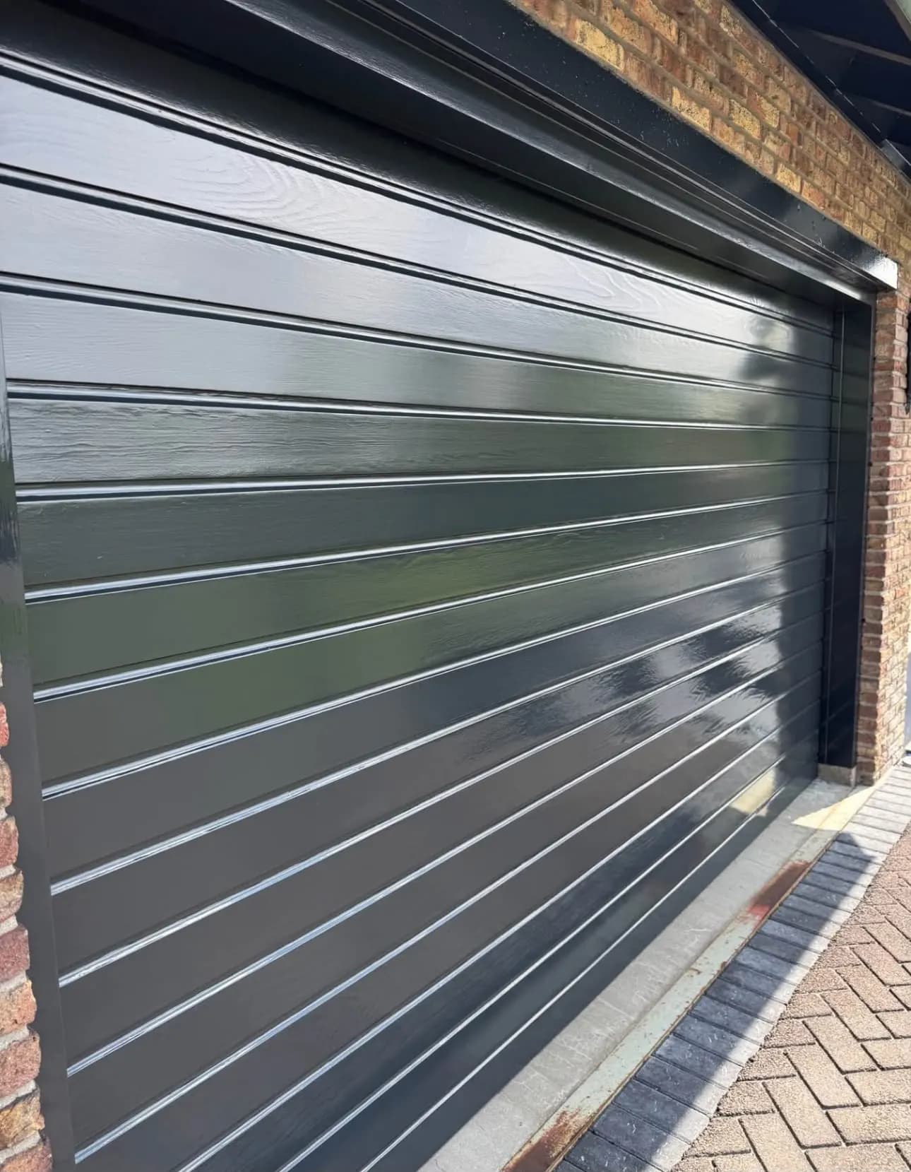 Geschilderde garagedeur in Den Haag met glanzende donkere lak